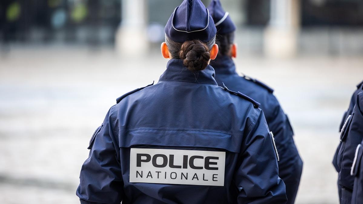 Policière de dos avec l'inscription "police nationale" sur son gilet tactique