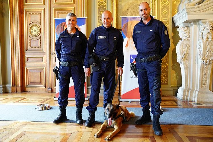 Des policiers de l'équipe cynophile posent avec un chien de la police