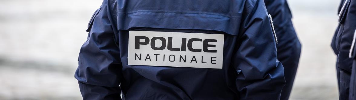 Policière de dos avec l'inscription "police nationale" sur son gilet tactique
